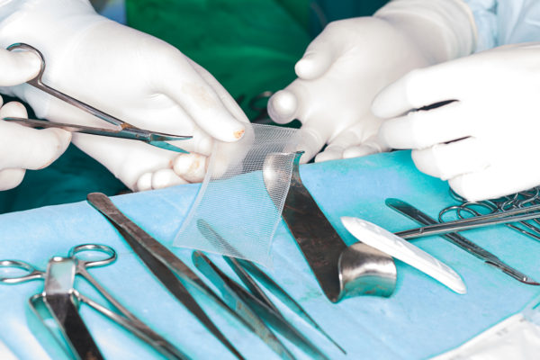 surgeon chops mesh for hernia