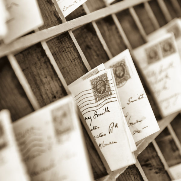 old fashioned letters and postcards sorted into old fashioned wooden mail box slots. 1930s postmarked British stamp at frame centre.